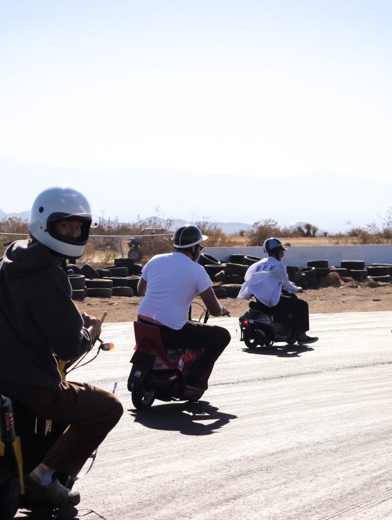 A group of people on scooters riding on a race track