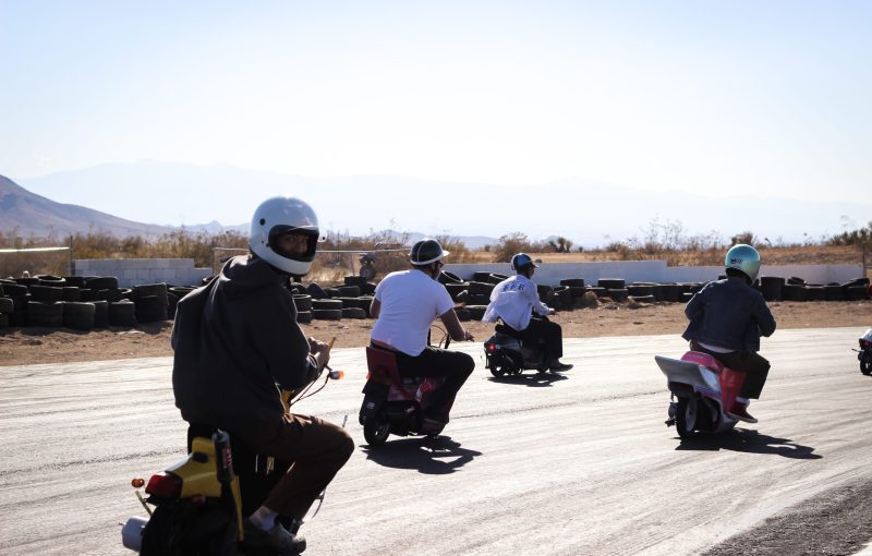 A group of people on scooters riding on a race track