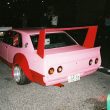Custom pink and red car with a prominent rear wing and wide tires in Japan, displaying license plate number 33-33.