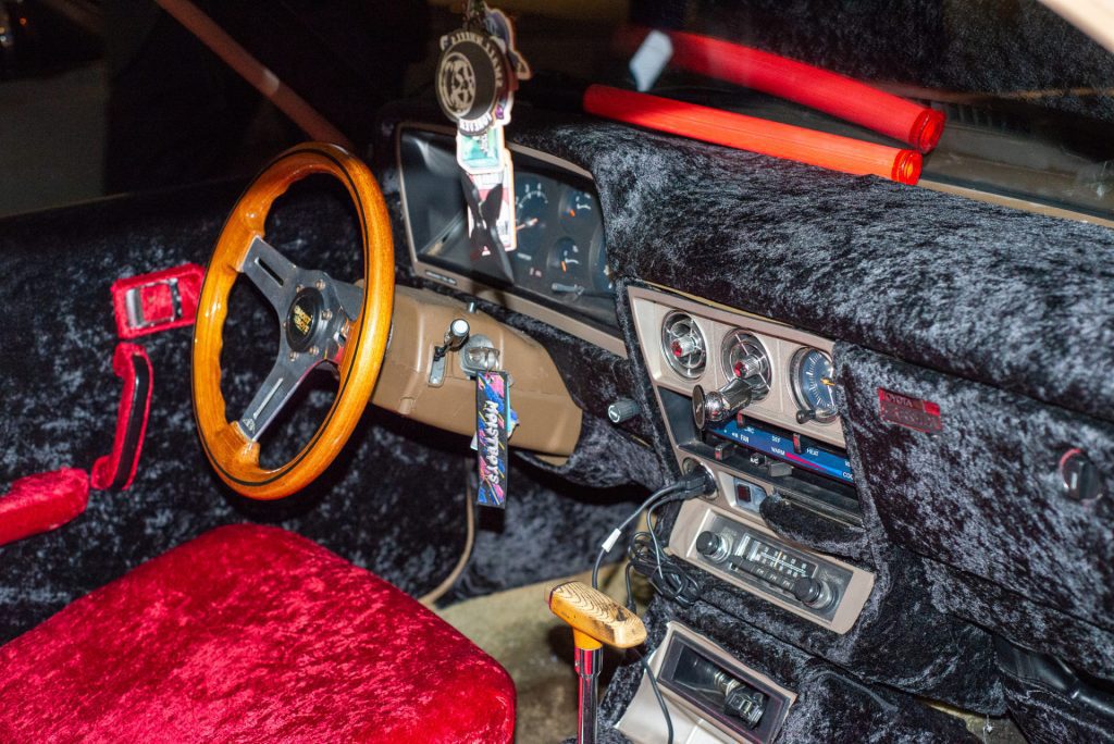 Vintage Toyota Celica GT interior with plush red seats, wood steering wheel, and retro dashboard gauges.