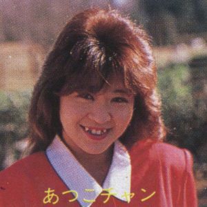 Smiling woman with red hair wearing a red outfit. The text in Japanese reads あつこチャン (Atsuko-chan).