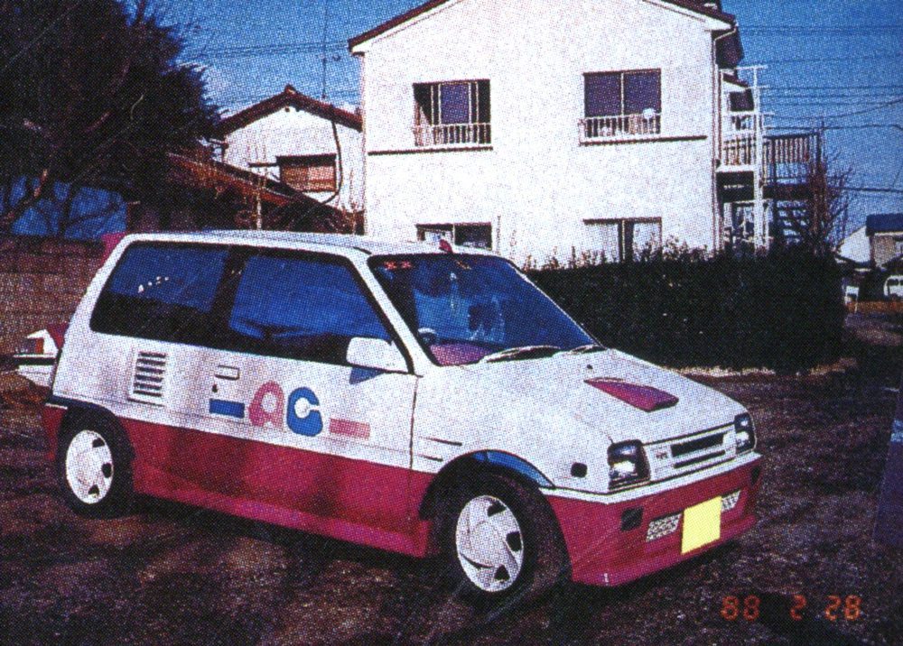Retro white and pink compact car parked in front of Japanese house, photographed on February 28, 1998.