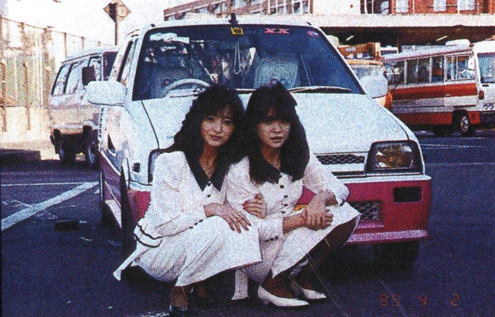 Two women in white outfits pose in front of a white car with a pink bumper, 1980s Japan. Date: April 2, 1989.