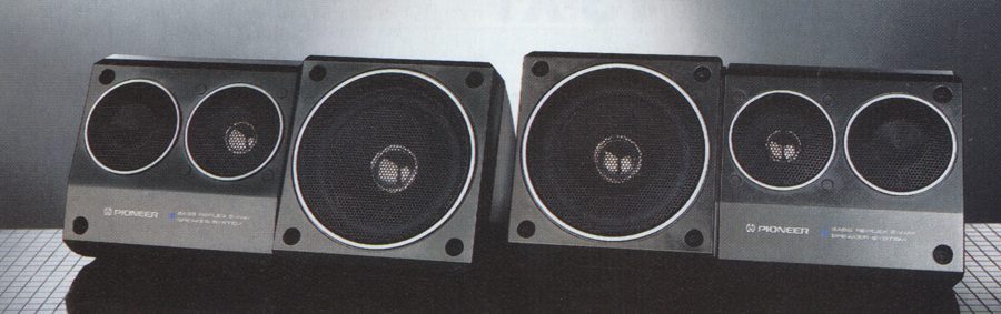 Four Pioneer speakers displayed side by side on a patterned surface, showcasing different sizes and designs in a studio setting.