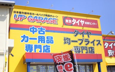 Yellow building with signs for Up Garage and Japanese text advertising a used car parts specialty store and a tire store.