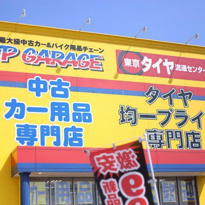 Yellow building with signs for Up Garage and Japanese text advertising a used car parts specialty store and a tire store.