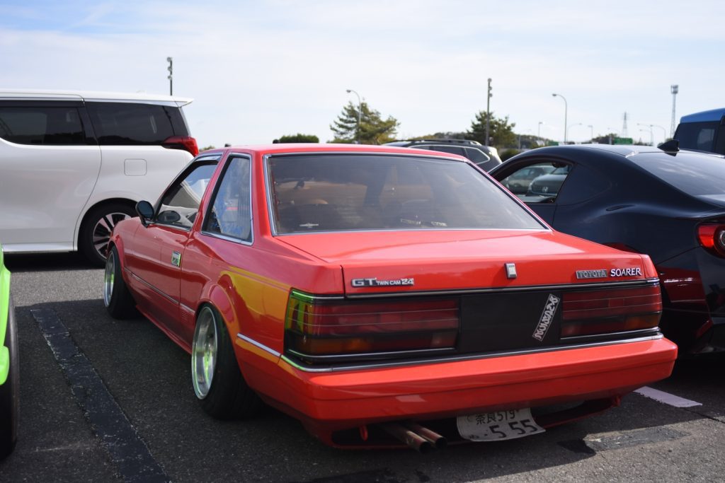 Red Toyota Soarer parked in a car lot, featuring 'GT Twin Cam 24' and Japanese license plate number 519 (519 is a wordplay in Japanese meaning, Thank you).