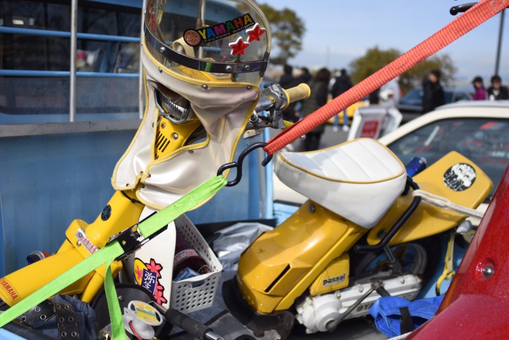 Alt text: Yellow Yamaha motorbike with helmet and accessories, including a sticker showing the Japanese word for 'courage'.