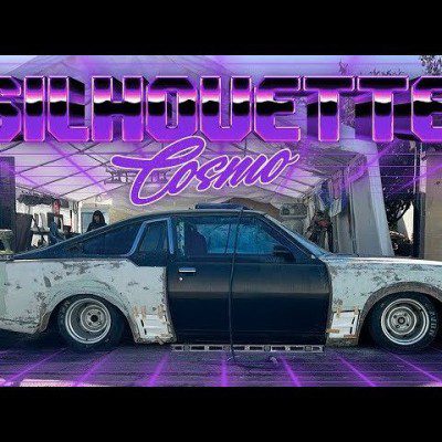 Modified classic car under a canopy with neon text Silhouette Cosmo above, highlighting custom automotive restoration.