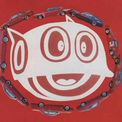Smiling white cartoon face surrounded by red cars on a bright red background. Text ラリー translates to rally.