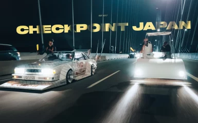 Vintage cars on a Japanese bridge at night with the text Checkpoint Japan.