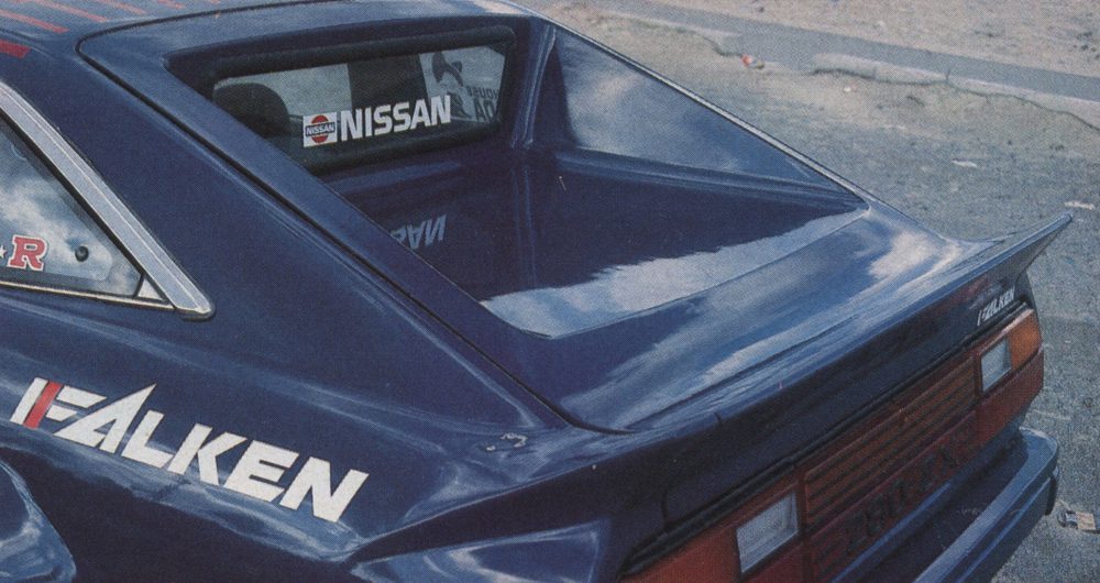 Blue Nissan sports car with Falken branding, rear view. Nissan logo and stickers on the rear window.