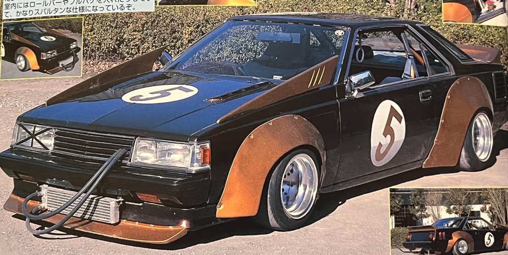 Customized black race car with number 5, orange accents, aftermarket wheels, and unique front bumper. Japanese text in the image.