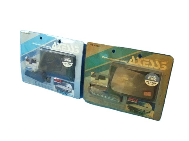 Two packages of Car Mate AXESS side mirrors for left-hand drive vehicles, in blue and green packaging.