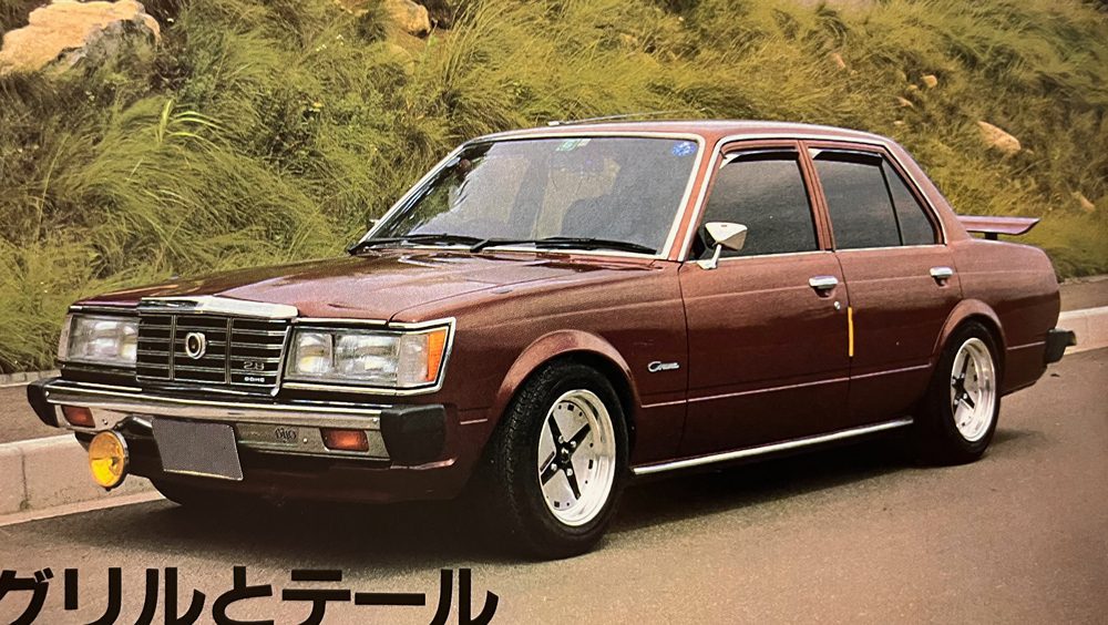 Vintage brown sedan parked on the roadside with グリル と テール (Grille and Tail) in Japanese text at the bottom left.