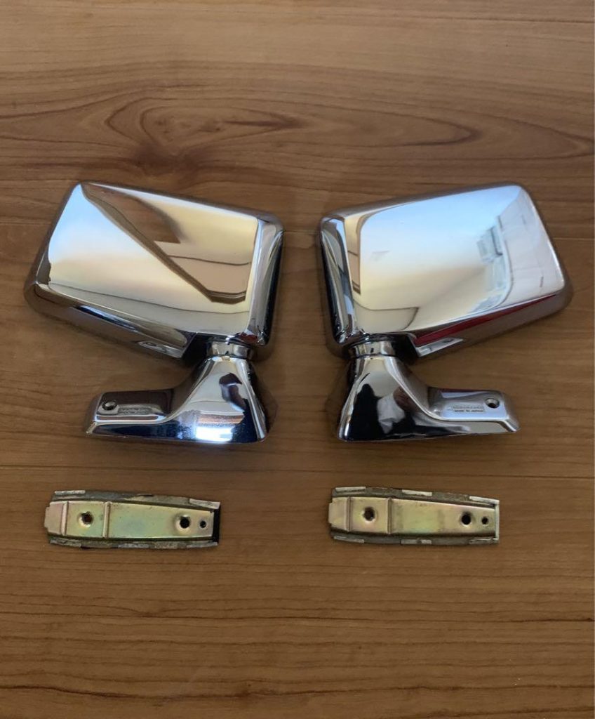 Vintage chrome side mirrors with brackets on wooden surface, ideal for retro car restoration projects.