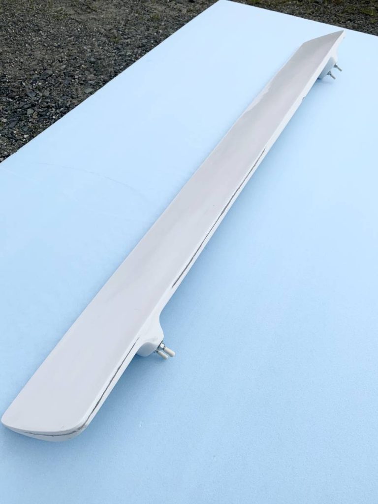 White car spoiler on light blue background, shown at an angle. Car part photograph for auto accessory listings.