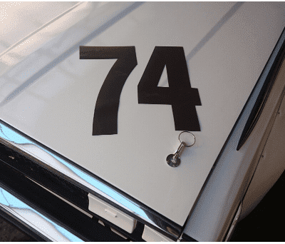 Alt text: Close-up of a car hood with the number 74 and a keychain lying on it