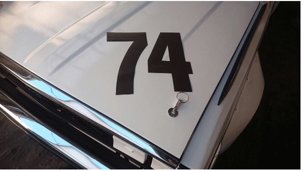 Alt text: Close-up of a car hood with the number 74 and a keychain lying on it