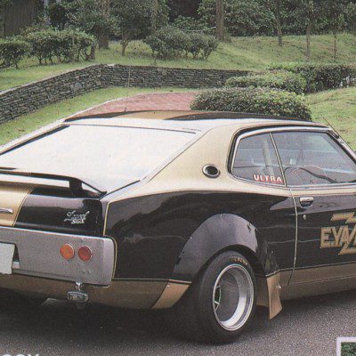 Vintage customized Eizo car with Ultra and E.YAZAWA decals parked in a green park with stone wall.