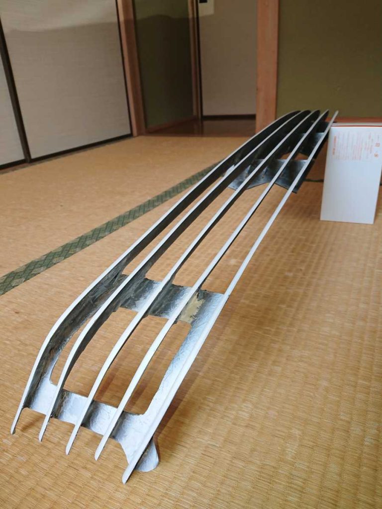 Futuristic art sculpture displayed on tatami flooring in traditional Japanese room with informational plaque in Japanese text.