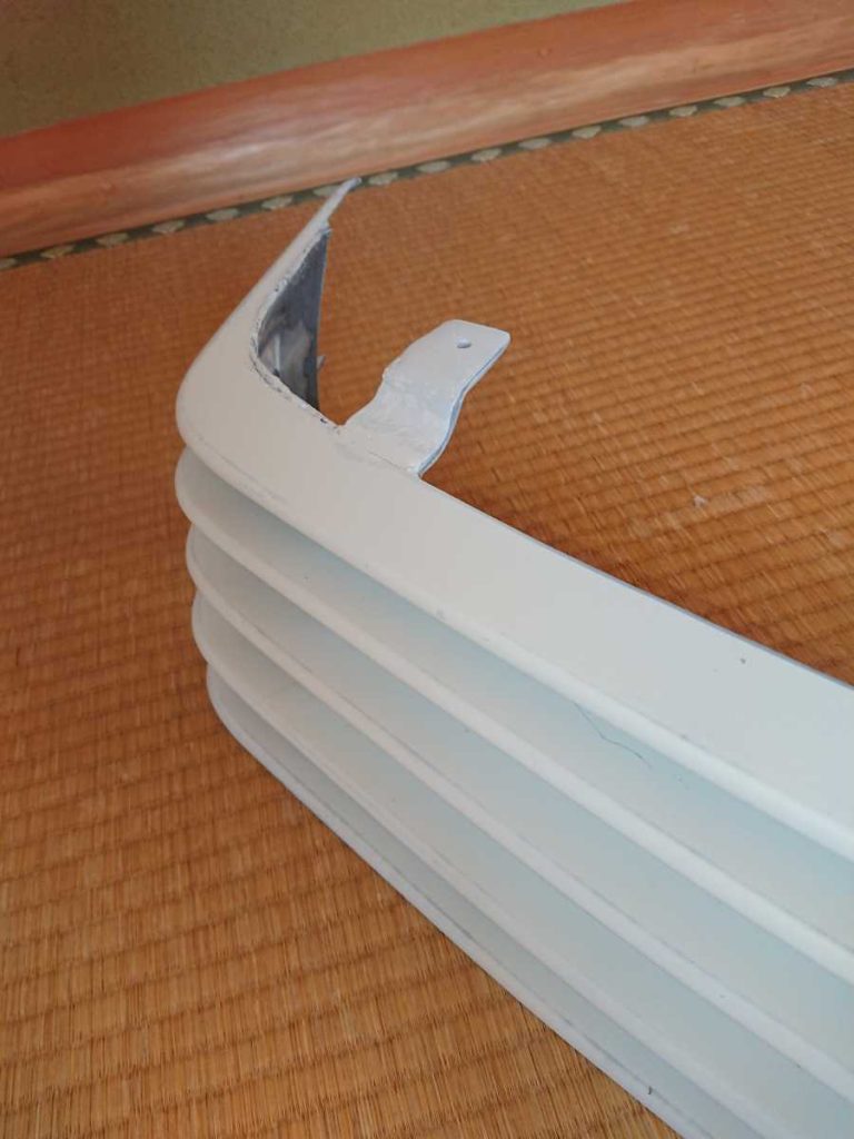 Close-up of a white plastic vent cover placed on a tatami mat floor near a wall in a traditional Japanese room.