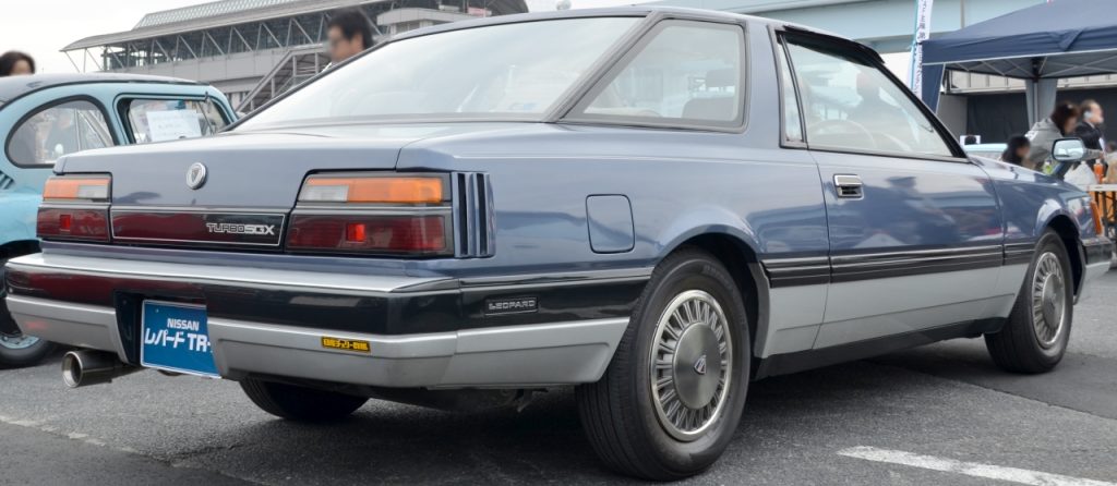 Vintage Nissan Leopard TR-X Turbo at a car show, featuring a unique blue and grey exterior design and classic detailing.