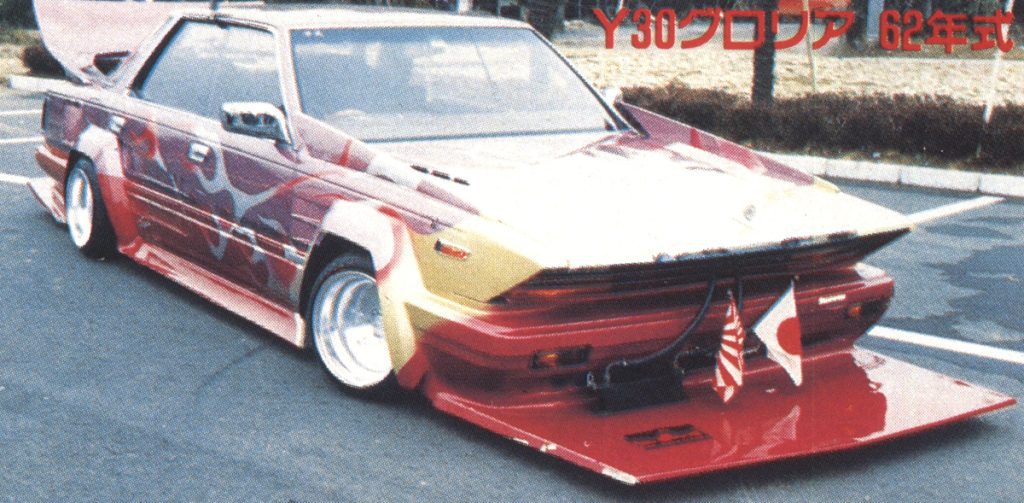 Customized Y30 Gloria 1987 with elaborate paint job and modifications, featuring Japanese and American flags at the front.