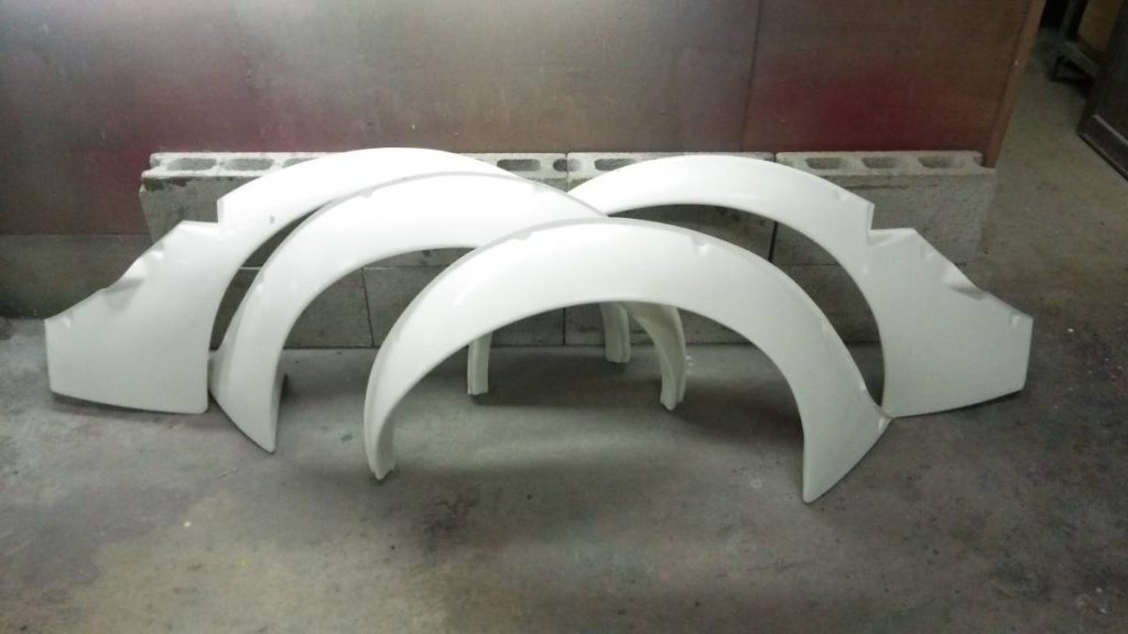 Set of four white Nissan Fairlady Z S30 Works fender flares on a cement block background, perfect for vehicle customization.