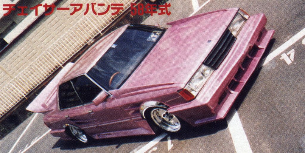 Pink customized Toyota Chaser 1983 model in a parking lot, with Japanese text チェイサーアバンテ 58年式 translating to Chaser Avante 1983 model.