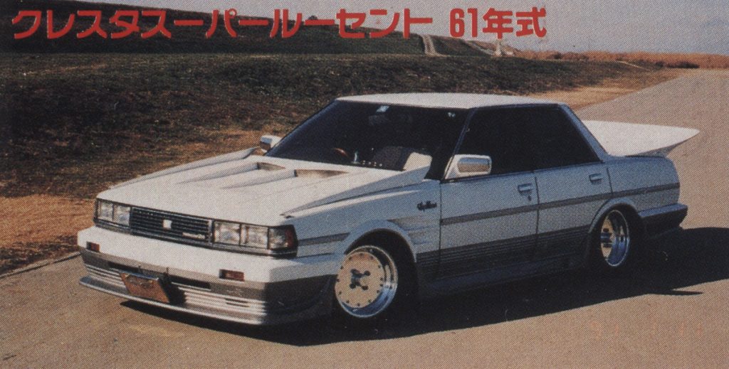 Alt text: 1986 Toyota Cresta Pearl Scent, modified white classic car with wide body kit and custom wheels on rural road.(Note: クレスタスパールーセント 61年式 translates to Cresta Pearl Scent 61st year type, which refers to the 1986 Toyota Cresta