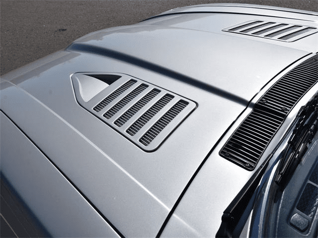 Close-up of a sleek silver car hood with stylish air vents for improved engine cooling and performance.