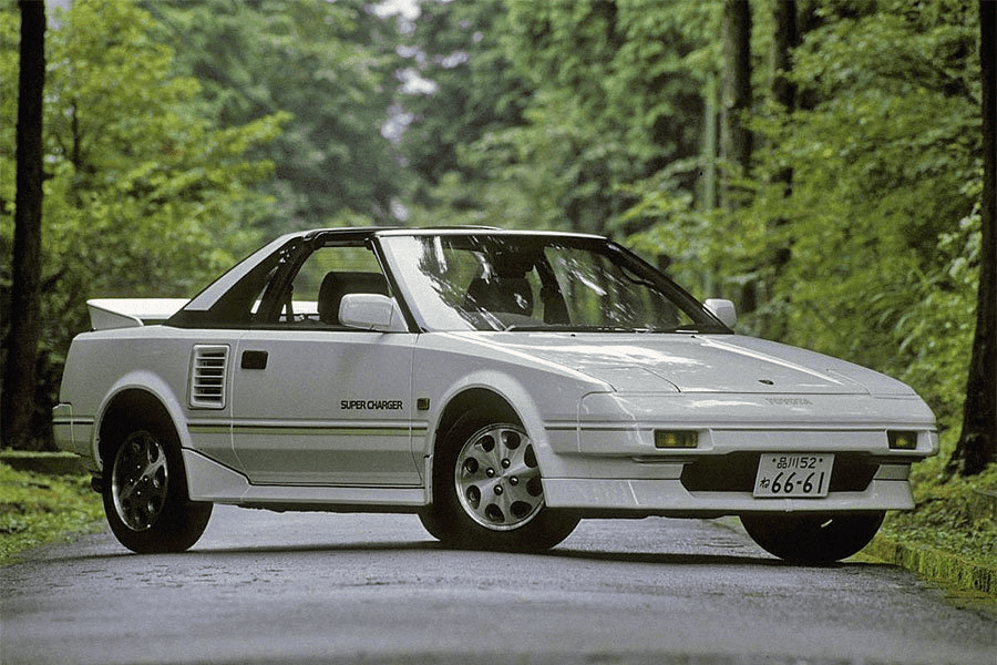 White Toyota MR2 Super Charger sports car parked on a scenic forest road, featuring Japanese license plate number 66-61.