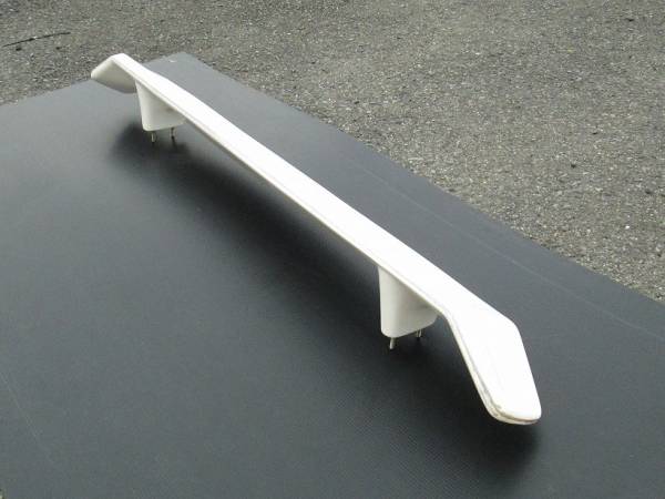 White car spoiler for rear deck installation, set on a black mat background, designed for improved aerodynamic performance.