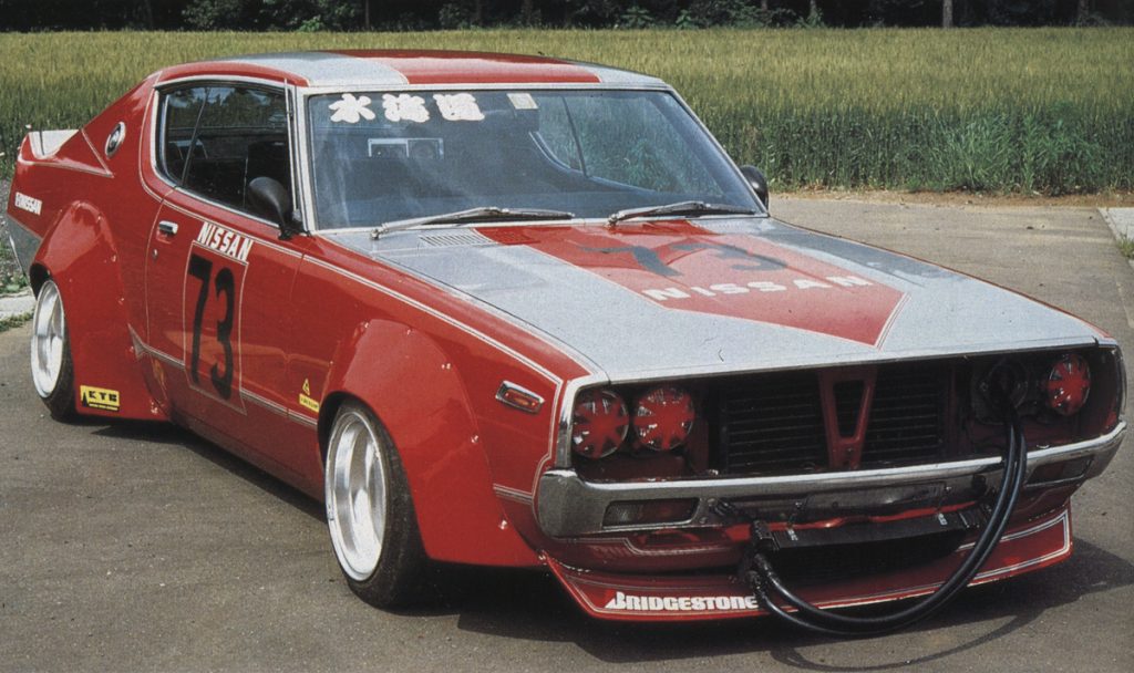 Classic red Nissan race car with the number 73, featuring Japanese text 水曜道 (Wednesday) on the windshield.