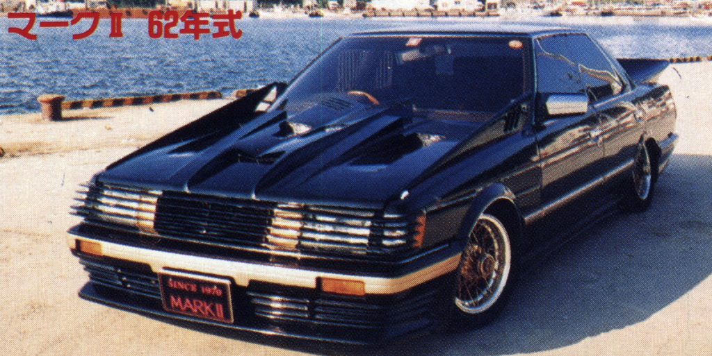 Modified 1962 Toyota Mark II with a custom black and gold paint job, parked by the water. Japanese text reads Mark II 62 SS.