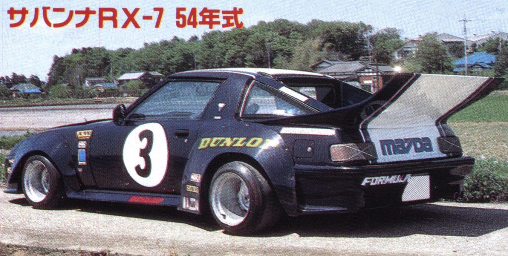 Vintage Mazda RX-7 race car with large rear spoiler, サバンナRX-7 54年式 translates to Savanna RX-7, the 1979 model.