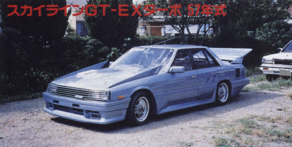 Silver classic Nissan Skyline GT-EX Turbo 1982 model parked with trees in the background and Japanese text above.