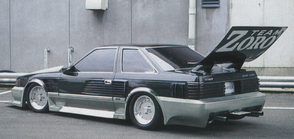 Modified vintage car with Team Zoro spoiler and custom body kit, parked in an urban area.