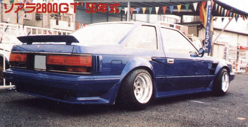 Vintage Toyota Soarer 2800GT from 1981 with body kit and spoiler in an outdoor car show setting.