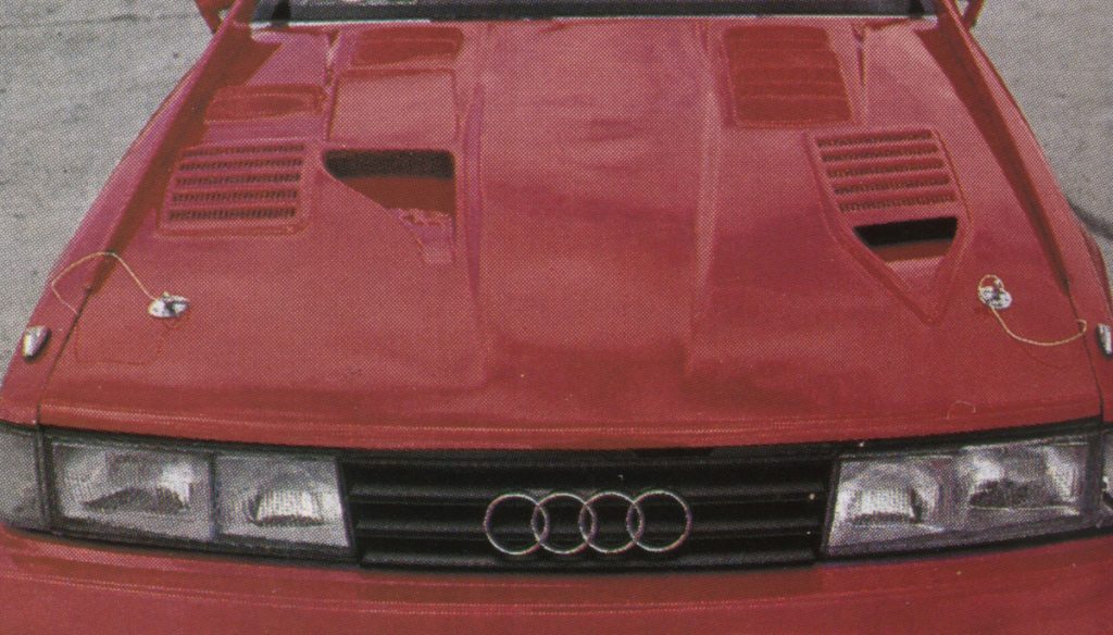 Red Audi car front view with customized hood featuring multiple air vents and safety locks.