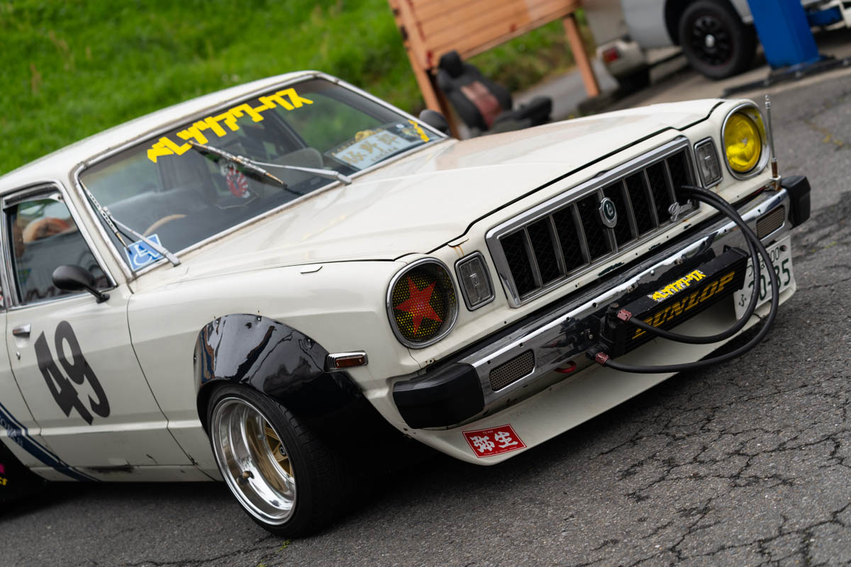 Vintage race car with the number 49, custom decals, and modifications including custom headlights and DUNLOP front bumper.