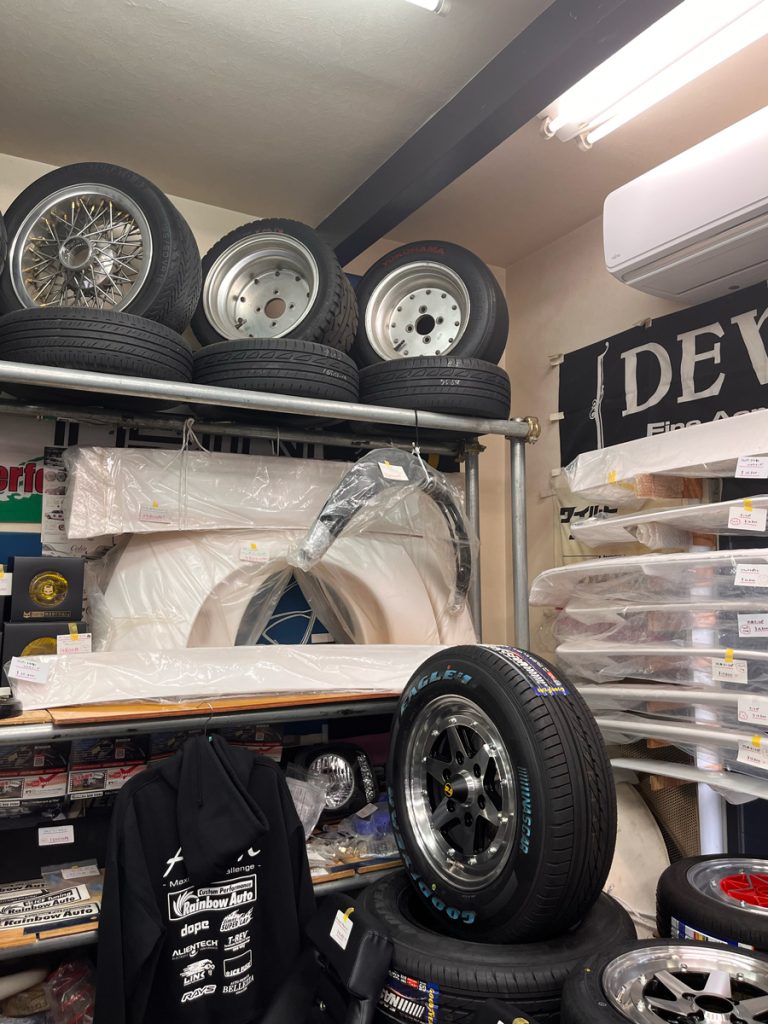 Automotive parts shop with various car tires, wheels, and accessories for sale, including Yokohama and Goodyear brands.