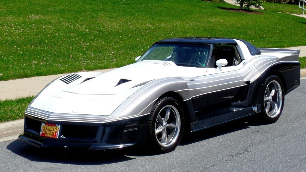 Modified classic car with sleek silver and black design parked on a suburban street, showcasing custom bodywork and wheels.