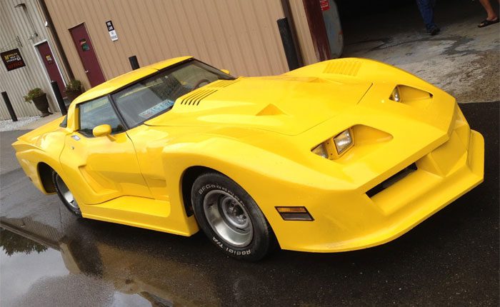 Bright yellow sports car with a sleek design parked outside a garage on a wet surface.