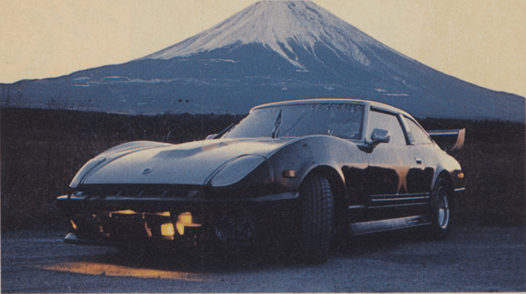 Vintage black car parked in front of Mount Fuji during sunset.