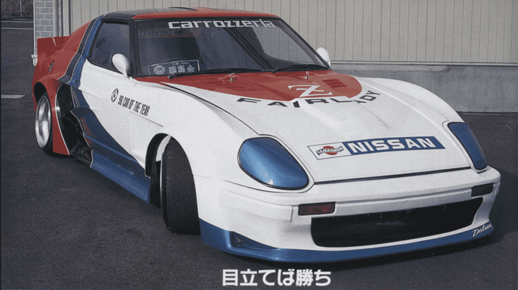 Modified vintage Nissan Fairlady Z29 race car with custom red, white, and blue paint and decals. Japanese text reads, Stand out to win.