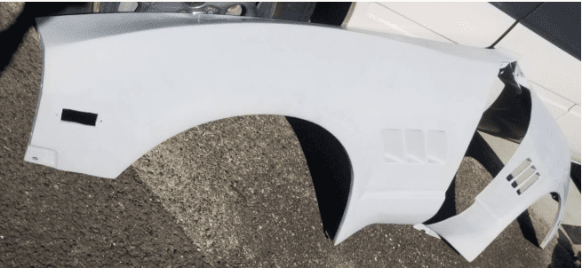 White car fender on a paved surface, showcasing vehicle part detail for automotive repair or replacement.