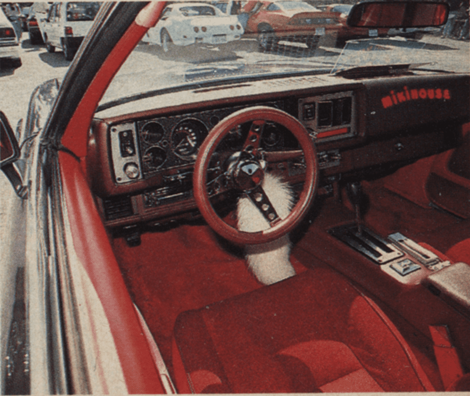 Vintage car interior with red leather seats, wooden steering wheel, dashboard featuring mikihouse in Japanese katakana: ミキハウス.