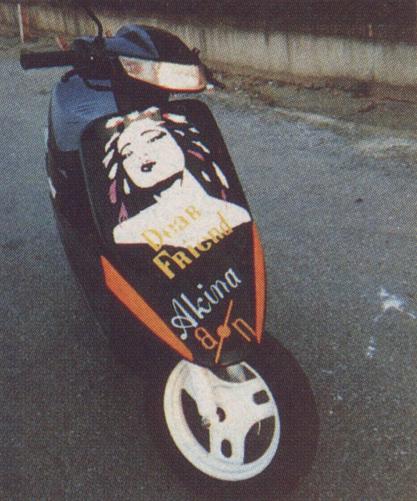 Customized scooter featuring a painted woman's face, Dear Friend text, and Akina 87 writing on the front cover.